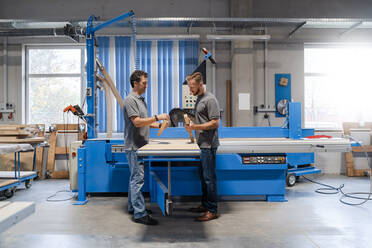 Two male carpenters talking in production hall - DIGF14164