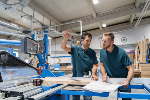 Zwei männliche Schreiner arbeiten zusammen in einer Produktionshalle - DIGF14176