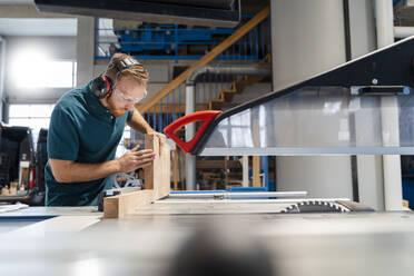 Carpenter cutting plank on circular saw in production hall - DIGF14188