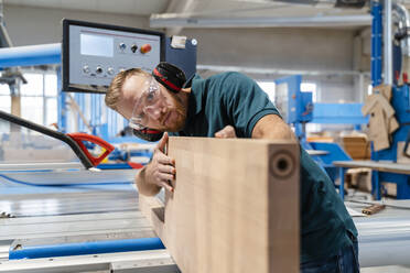 Carpenter measuring wooden plank in production hall - DIGF14189