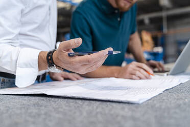 Hand of man holding pen while talking over documents with coworker - DIGF14193