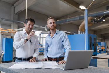 Two carpenters talking over documents in production hall - DIGF14200