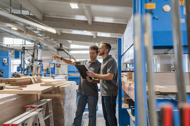 Two carpenters standing and talking in production hall - DIGF14242