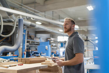 Porträt eines Schreiners in einer Produktionshalle mit einem Klemmbrett in der Hand - DIGF14247