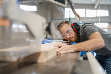 Portrait of carpenter cutting plank of wood - DIGF14257