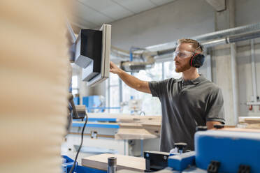 Porträt eines Schreiners, der die Schalttafel in einer Produktionshalle bedient - DIGF14258