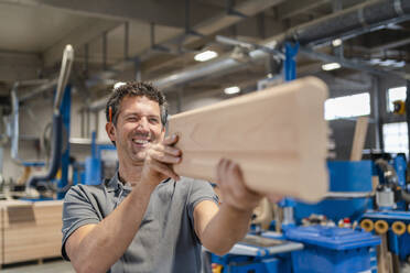 Portrait of carpenter examining plank of wood - DIGF14263