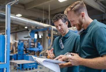 Two carpenters standing and talking in production hall - DIGF14269