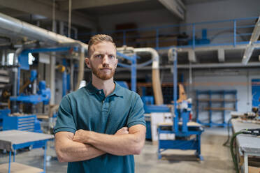 Portrait of carpenter posing in production hall with crossed arms - DIGF14273