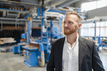 Portrait of well-dressed carpenter standing in production hall - DIGF14296