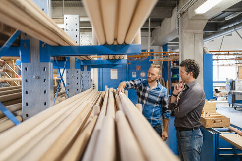 Zwei Zimmerleute prüfen Holzstangen in der Produktionshalle - DIGF14313