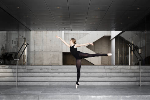 Ballerina in black leotard in modern concrete building - JPTF00637