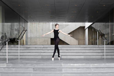 Ballerina in black leotard in modern concrete building - JPTF00641