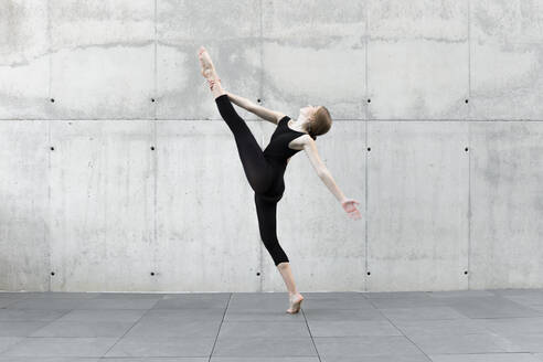 Tänzerin im schwarzen Trikot tanzt vor einer Betonwand - JPTF00652