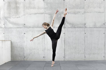 Tänzerin im schwarzen Trikot tanzt vor einer Betonwand - JPTF00655