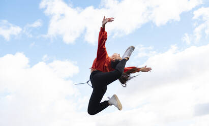 Long-haired brunette jumping against sky - JCCMF00765