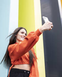 Porträt einer schönen Brünetten, die ein Selfie mit ihrem Smartphone macht - JCCMF00779