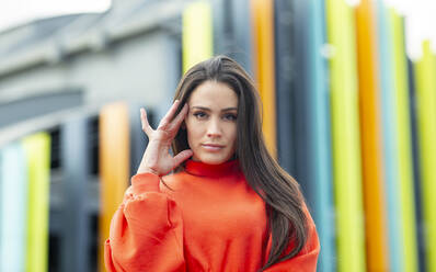 Portrait of beautiful brunette standing outdoors with hand in hair - JCCMF00785