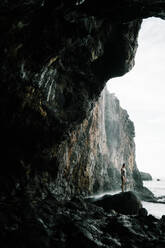 Stimmungsvolles Bild einer Frau unter einem Wasserfall am Strand - CAVF91605