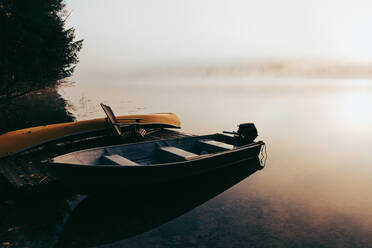 Leerer Steg mit festgemachten Booten an einem nebligen Morgen auf einem ruhigen See. - CAVF91651