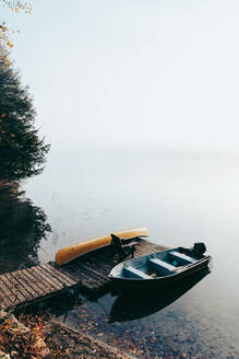 Leerer Steg mit festgemachten Booten an einem nebligen Morgen auf einem ruhigen See. - CAVF91653