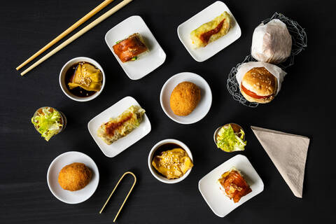 Top view of various tasty fusion food arranged on black table in restaurant stock photo