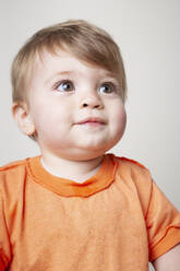 Kleiner Junge in orangefarbenem T-Shirt schaut nach oben - ISPF00005