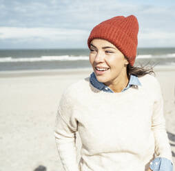 Portrait of woman wearing knit hat standing on beach - UUF22501