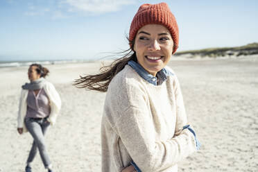 Portrait of woman wearing knit hat standing on beach - UUF22502