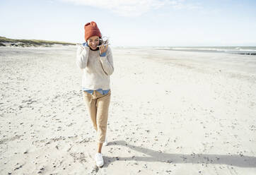 Portrait of woman wearing knit hat talking on smart phone at beach - UUF22509