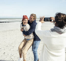 Eine Gruppe von Freunden macht Smartphone-Fotos am Sandstrand - UUF22517