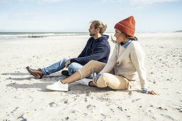 Junges Paar sitzt zusammen am Strand - UUF22521