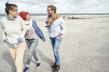 Gruppe von Freunden, die gemeinsam am Sandstrand spazieren gehen - UUF22540