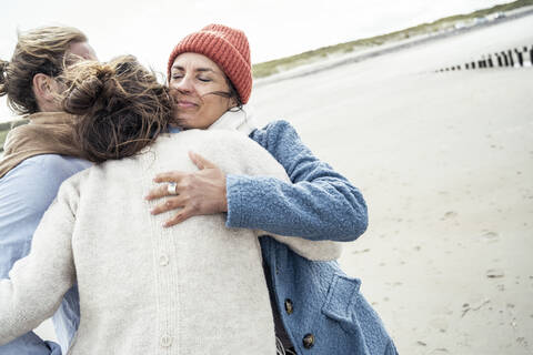 Group of friends hugging on beach stock photo