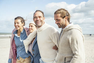 Group of adult friends standing together on coastal beach - UUF22556