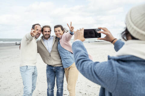 Group of friends taking smart phone photos at beach stock photo