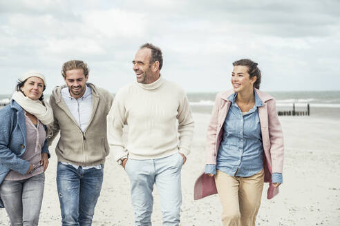 Gruppe erwachsener Freunde, die Seite an Seite am Sandstrand spazieren gehen - UUF22574