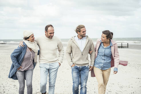 Gruppe erwachsener Freunde, die Seite an Seite am Sandstrand spazieren gehen - UUF22575