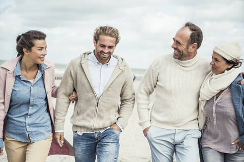 Gruppe erwachsener Freunde, die Seite an Seite am Sandstrand spazieren gehen - UUF22577