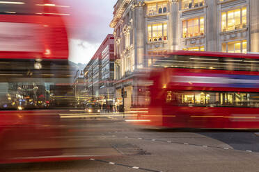 UK, London, Roter Doppeldeckerbus überquert Oxford Circus Kreuzung in der Abenddämmerung, unscharf - WPEF03859