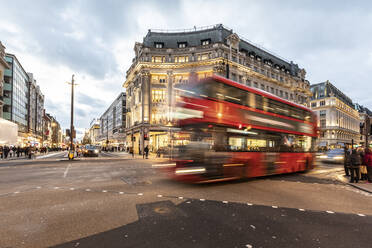 UK, London, Roter Doppeldeckerbus überquert Oxford Circus Kreuzung in der Abenddämmerung, unscharf - WPEF03860