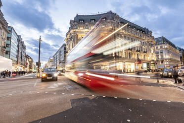 UK, London, Roter Doppeldeckerbus überquert Oxford Circus Kreuzung in der Abenddämmerung, unscharf - WPEF03861