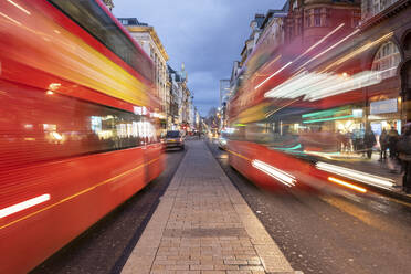 UK, London, Rote Doppeldeckerbusse auf der Oxford Street in der Abenddämmerung, unscharf - WPEF03862