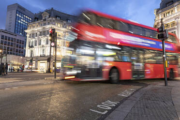 UK, London, Roter Doppeldeckerbus überquert Oxford Circus Kreuzung bei Nacht, unscharf - WPEF03864