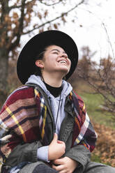 Smiling teenage girl in hat in Autumn landscape - JAQF00167