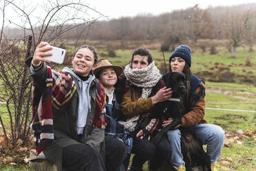 Family with dog taking selfie in Autumn landscape - JAQF00168