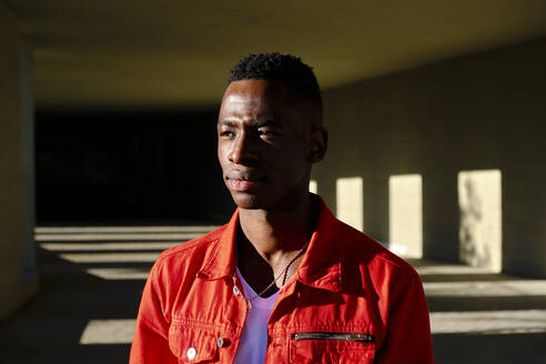 Pensive young man in red jacket outdoors - AODF00206