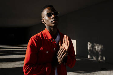 Junger Mann in roter Jacke und Sonnenbrille im Freien - AODF00214