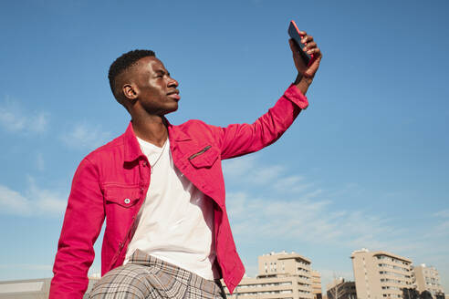 Young man in red jacket taking selfie outdoors - AODF00222