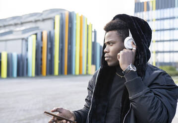 Young man listening to music in city - JCCMF00816